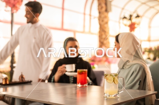 قضاء وقت ممتع في الخارج، الاستمتاع بتناول المشروبات الساخنة، حوارات ونقاشات عائلية، مفهوم الألفة والمحبة بين الأهل والأصدقاء, اصدقاء عرب خليجيون سعوديون يجلسون في احدى الكافيهات الراقية، ايماءات السعادة والسرور