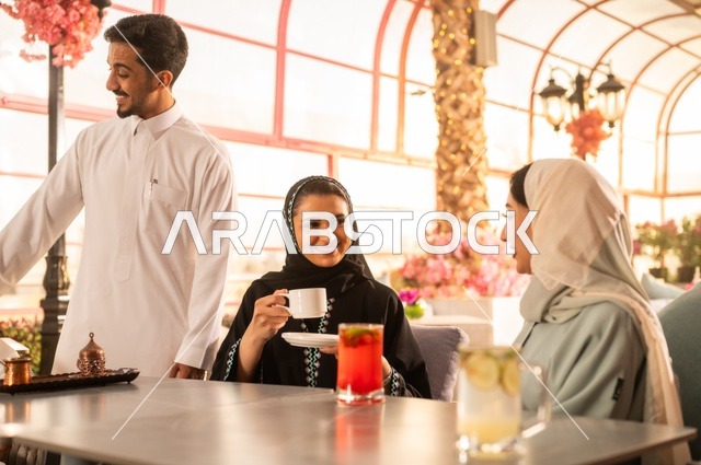 قضاء وقت ممتع في الخارج، الاستمتاع بتناول المشروبات الساخنة، حوارات ونقاشات عائلية، مفهوم الألفة والمحبة بين الأهل والأصدقاء, اصدقاء عرب خليجيون سعوديون يجلسون في احدى الكافيهات الراقية، ايماءات السعادة والسرور