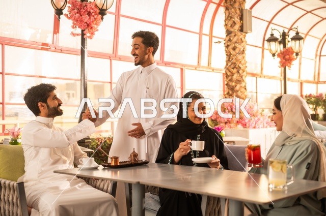 قضاء وقت ممتع في الخارج، الاستمتاع بتناول المشروبات الساخنة، حوارات ونقاشات عائلية، مفهوم الألفة والمحبة بين الأهل والأصدقاء, اصدقاء عرب خليجيون سعوديون يجلسون في احدى الكافيهات الراقية، ايماءات السعادة والسرور