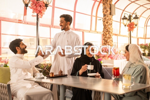 قضاء وقت ممتع في الخارج، الاستمتاع بتناول المشروبات الساخنة، حوارات ونقاشات عائلية، مفهوم الألفة والمحبة بين الأهل والأصدقاء, اصدقاء عرب خليجيون سعوديون يجلسون في احدى الكافيهات الراقية، ايماءات السعادة والسرور