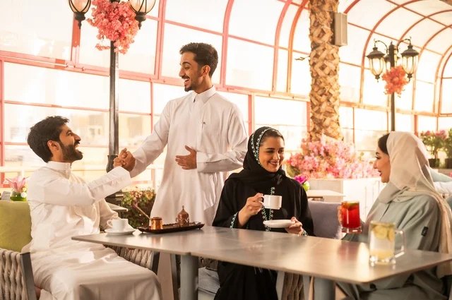 قضاء وقت ممتع في الخارج، الاستمتاع بتناول المشروبات الساخنة، حوارات ونقاشات عائلية، مفهوم الألفة والمحبة بين الأهل والأصدقاء, اصدقاء عرب خليجيون سعوديون يجلسون في احدى الكافيهات الراقية، ايماءات السعادة والسرور