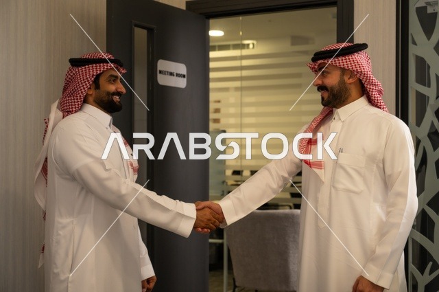عقد صفقات عمل جديدة ناجحة بين رجال الأعمال، صداقات وتعارف وبناء علاقات اجتماعية، الشراكة في الأعمال والمشاريع، رجلان عربيان خليجيان سعوديان يرتديان الشماغ والثوب التقليدي يقومان بمصافحة بعضهما، توسيع مجالات العمل