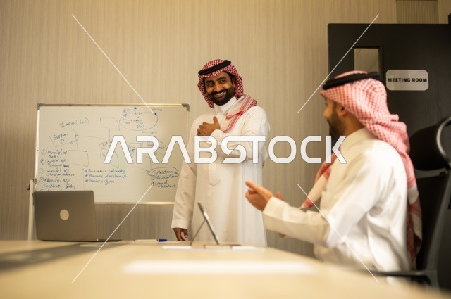 استعمال السبورة لتوضيح العمليات والاجراءات المتبعة في الشركة، العمل الجماعي وروح الفريق، مناقشة خطط العمل، استخدام اللابتوب في تدوين الملاحظات، الاحترافية والتفاني في الإنجاز، فريق عربي خليجي سعودي في اجتماع داخل المكتب، ضمان فهم واضح وشامل للاعمال