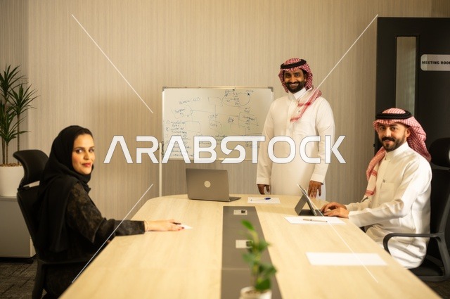 Teamwork and team spirit, discussing work plans, using laptops to take notes, professionalism and dedication to achievement, a Saudi Gulf Arab team in a meeting inside the office, ensuring a clear and comprehensive understanding of the work, clarifying the processes and procedures followed in the company.