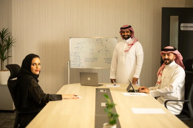 العمل الجماعي وروح الفريق، مناقشة خطط العمل، استخدام اللابتوب في تدوين الملاحظات، الاحترافية والتفاني في الإنجاز، فريق عربي خليجي سعودي في اجتماع داخل المكتب، ضمان فهم واضح وشامل للاعمال، توضيح العمليات والاجراءات المتبعة في الشركة