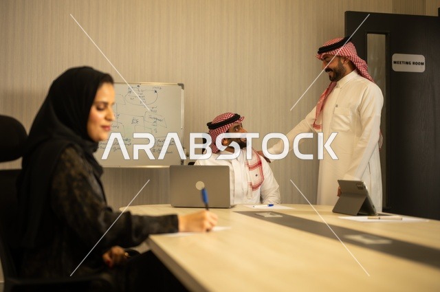 العمل الجماعي وروح الفريق، مناقشة خطط العمل، استخدام اللابتوب في تدوين الملاحظات، الاحترافية والتفاني في الإنجاز، فريق عربي خليجي سعودي في اجتماع داخل المكتب، ضمان فهم واضح وشامل للاعمال، توضيح العمليات والاجراءات المتبعة في الشركة
