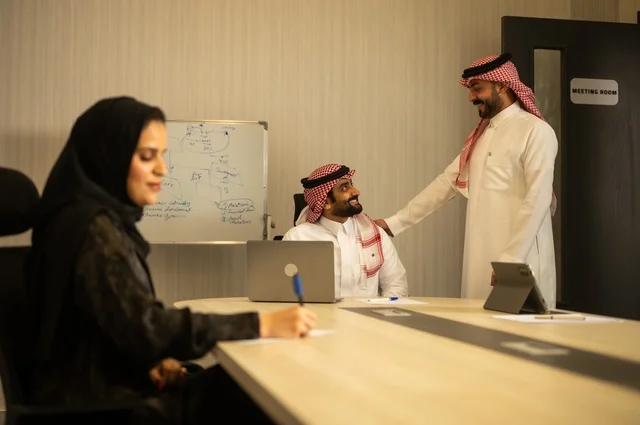 Teamwork and team spirit, discussing work plans, using laptops to take notes, professionalism and dedication to achievement, a Saudi Gulf Arab team in a meeting inside the office, ensuring a clear and comprehensive understanding of the work, clarifying the processes and procedures followed in the company.