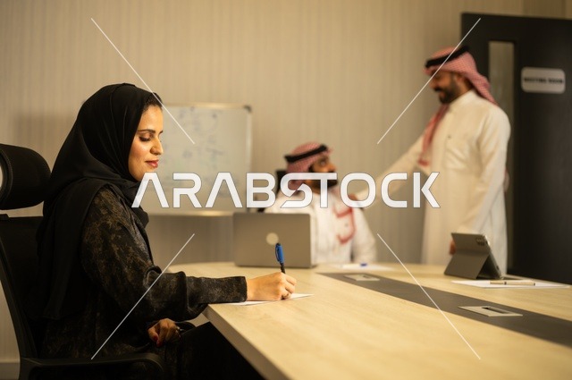 Teamwork and team spirit, discussing work plans, using laptops to take notes, professionalism and dedication to achievement, a Saudi Gulf Arab team in a meeting inside the office, ensuring a clear and comprehensive understanding of the work, clarifying the processes and procedures followed in the company.