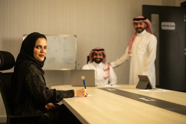 Teamwork and team spirit, discussing work plans, using laptops to take notes, professionalism and dedication to achievement, a Saudi Gulf Arab team in a meeting inside the office, ensuring a clear and comprehensive understanding of the work, clarifying the processes and procedures followed in the company.