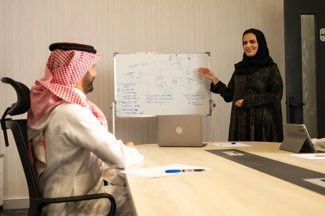 العمل الجماعي وروح الفريق، مناقشة خطط العمل، استخدام اللابتوب في تدوين الملاحظات، الاحترافية والتفاني في الإنجاز، فريق عربي خليجي سعودي في اجتماع داخل المكتب، ضمان فهم واضح وشامل للاعمال، توضيح العمليات والاجراءات المتبعة في الشركة