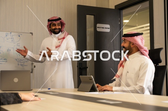 العمل الجماعي وروح الفريق، مناقشة خطط العمل، استخدام اللابتوب في تدوين الملاحظات، الاحترافية والتفاني في الإنجاز، فريق عربي خليجي سعودي في اجتماع داخل المكتب، ضمان فهم واضح وشامل للاعمال، توضيح العمليات والاجراءات المتبعة في الشركة