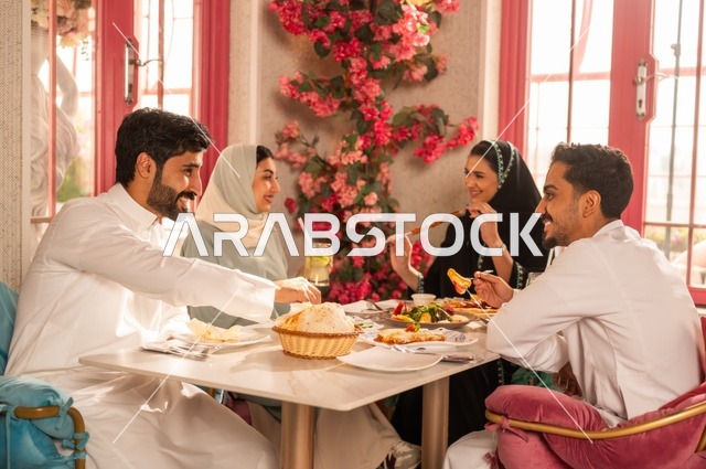 مشاركة الأصدقاء الأوقات الممتعة, الاستمتاع بتناول الغداء في المطعم, جلسة وناسة وتعارف، بناء علاقات اجتماعية ناجحة, تبادل الأحاديث والاخبار, عائلة عرب خليجيون سعوديون يجلسون على المائدة في إحدى المطاعم الراقية ويقومون بتناول الطعام بإيماءات السعادة والسرور