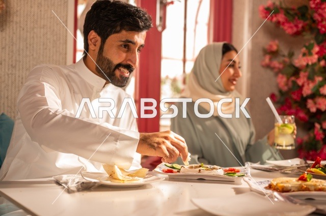 مشاركة الأصدقاء الأوقات الممتعة, الاستمتاع بتناول الغداء في المطعم, جلسة وناسة وتعارف، بناء علاقات اجتماعية ناجحة, تبادل الأحاديث والاخبار, عائلة عرب خليجيون سعوديون يجلسون على المائدة في إحدى المطاعم الراقية ويقومون بتناول الطعام بإيماءات السعادة والسرور