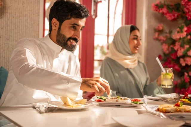 مشاركة الأصدقاء الأوقات الممتعة, الاستمتاع بتناول الغداء في المطعم, جلسة وناسة وتعارف، بناء علاقات اجتماعية ناجحة, تبادل الأحاديث والاخبار, عائلة عرب خليجيون سعوديون يجلسون على المائدة في إحدى المطاعم الراقية ويقومون بتناول الطعام بإيماءات السعادة والسرور