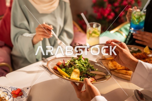 مشاركة الأصدقاء الأوقات الممتعة, الاستمتاع بتناول الغداء في المطعم, جلسة وناسة وتعارف، بناء علاقات اجتماعية ناجحة, تبادل الأحاديث والاخبار, عائلة عرب خليجيون سعوديون يجلسون على المائدة في إحدى المطاعم الراقية ويقومون بتناول الطعام بإيماءات السعادة والسرور