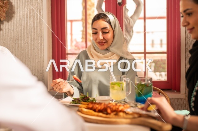 مشاركة الأصدقاء الأوقات الممتعة, الاستمتاع بتناول الغداء في المطعم, جلسة وناسة وتعارف، بناء علاقات اجتماعية ناجحة, تبادل الأحاديث والاخبار, عائلة عرب خليجيون سعوديون يجلسون على المائدة في إحدى المطاعم الراقية ويقومون بتناول الطعام بإيماءات السعادة والسرور