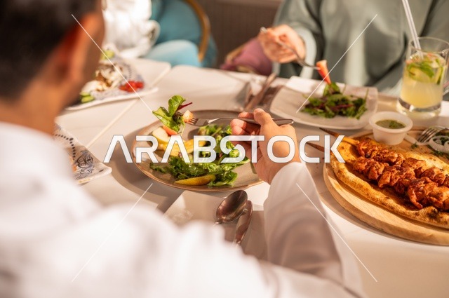 مشاركة الأصدقاء الأوقات الممتعة, الاستمتاع بتناول الغداء في المطعم, جلسة وناسة وتعارف، بناء علاقات اجتماعية ناجحة, تبادل الأحاديث والاخبار, عائلة عرب خليجيون سعوديون يجلسون على المائدة في إحدى المطاعم الراقية ويقومون بتناول الطعام بإيماءات السعادة والسرور