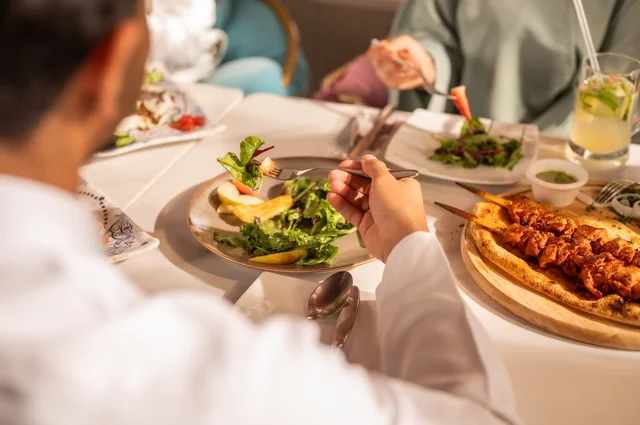 Sharing enjoyable times with friends, enjoying lunch at a restaurant, a fun gathering and getting to know each other, building successful social relationships, exchanging conversations and news, a family of Gulf Arab Saudis sitting at the table in one of the upscale restaurants, enjoying their meal with gestures of happiness and joy.