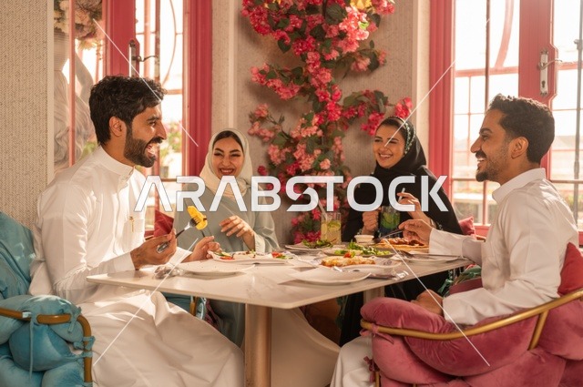 الاستمتاع بتناول الغداء في المطعم, جلسة وناسة وتعارف، بناء علاقات اجتماعية ناجحة, تبادل الأحاديث والاخبار, مشاركة الأصدقاء الأوقات الممتعة, عائلة عرب خليجيون سعوديون يجلسون على المائدة في إحدى المطاعم الراقية ويقومون بتناول الطعام بإيماءات السعادة والسرور