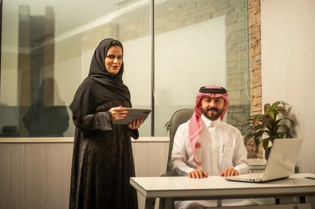 تعليم الموظفين الأساليب الجديدة في العمل لتحقيق أهداف الشركة، دمج العمل مع التقنية والتكنولوجيا، زميلان عربيان خليجيان سعوديان يقومان بإنجاز المهام عبر الحاسوب المحمول والتابلت، العمل الجماعي وروح الفريق الواحد