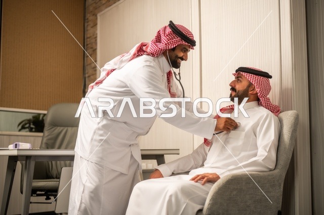 قياس  معدل ضربات القلب, مفهوم الطب والرعاية الصحية, المتابعة الدورية لفحص نبضات القلب, طبيب عربي خليجي سعودي يرتدي المعطف الطبي يقوم باستخدام سماعه الفحص الطبية لمريض يرتدي الشماغ والثوب التقليدي
