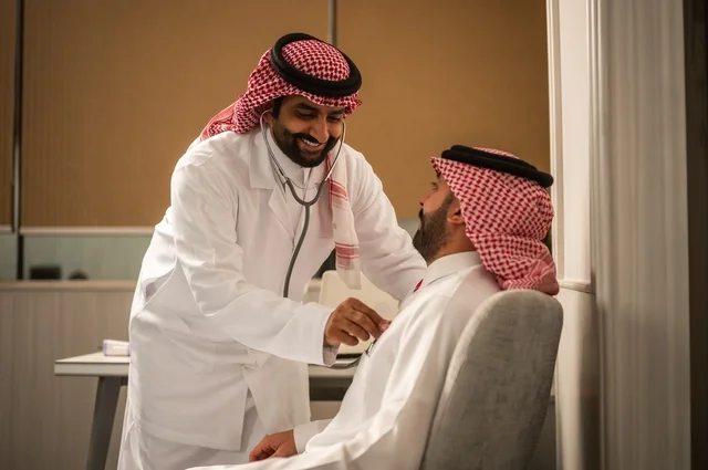 قياس  معدل ضربات القلب, مفهوم الطب والرعاية الصحية, المتابعة الدورية لفحص نبضات القلب, طبيب عربي خليجي سعودي يرتدي المعطف الطبي يقوم باستخدام سماعه الفحص الطبية لمريض يرتدي الشماغ والثوب التقليدي