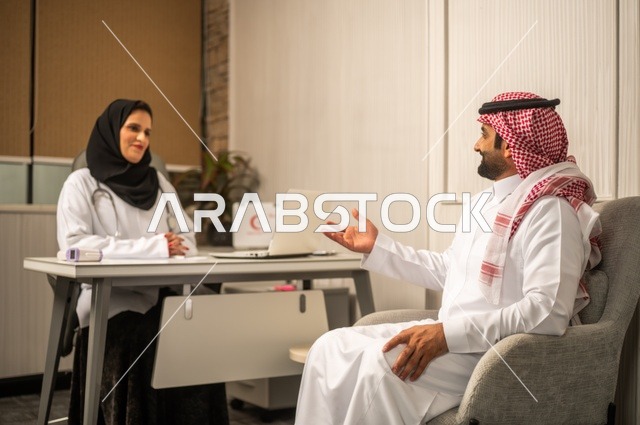 تقديم الاستشارات في المراكز الطبيه, العمل في القطاعات الصحية، متابعة السجل الطبي للمراجعين, تسجيل حالات المرضى على جهاز الحاسوب, طبيبة عربية خليجية سعودية ترتدي المعطف الأبيض تقوم بشرح الحالة المرضية لمريض يرتدي الشماغ والثوب التقليدي، الحوار مع المرضى لكشف الحالة
