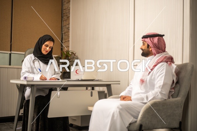 تقديم الاستشارات في المراكز الطبيه, العمل في القطاعات الصحية، متابعة السجل الطبي للمراجعين, تسجيل حالات المرضى على جهاز الحاسوب, طبيبة عربية خليجية سعودية ترتدي المعطف الأبيض تقوم بشرح الحالة المرضية لمريض يرتدي الشماغ والثوب التقليدي، الحوار مع المرضى لكشف الحالة