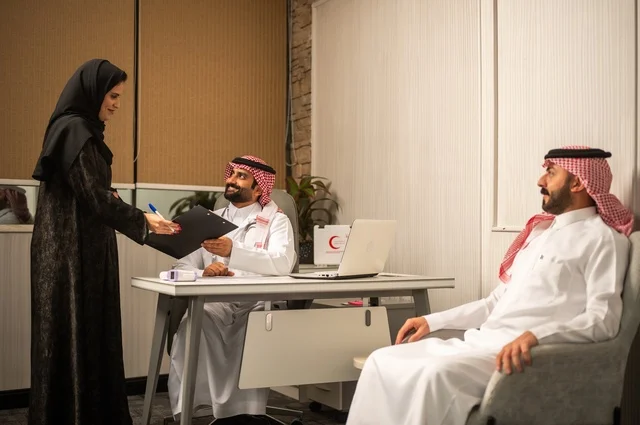 متابعة السجل الطبي للمراجعين, مساعدة تقوم بتسجيل حالات المرضى, طبيب عربي خليجي سعودي يرتدي المعطف الأبيض يقوم بشرح الحالة المرضية لمريض يرتدي الشماغ والثوب التقليدي، الحوار مع المرضى لكشف الحالة، تقديم الاستشارات في المراكز الطبيه, العمل في القطاعات الصحية