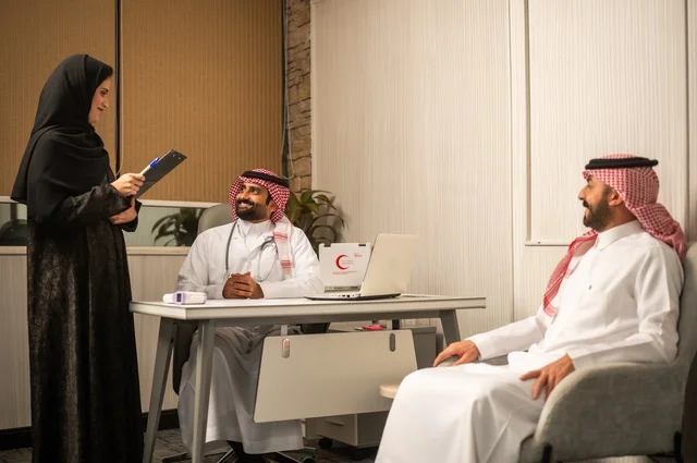 متابعة السجل الطبي للمراجعين, مساعدة تقوم بتسجيل حالات المرضى, طبيب عربي خليجي سعودي يرتدي المعطف الأبيض يقوم بشرح الحالة المرضية لمريض يرتدي الشماغ والثوب التقليدي، الحوار مع المرضى لكشف الحالة، تقديم الاستشارات في المراكز الطبيه, العمل في القطاعات الصحية