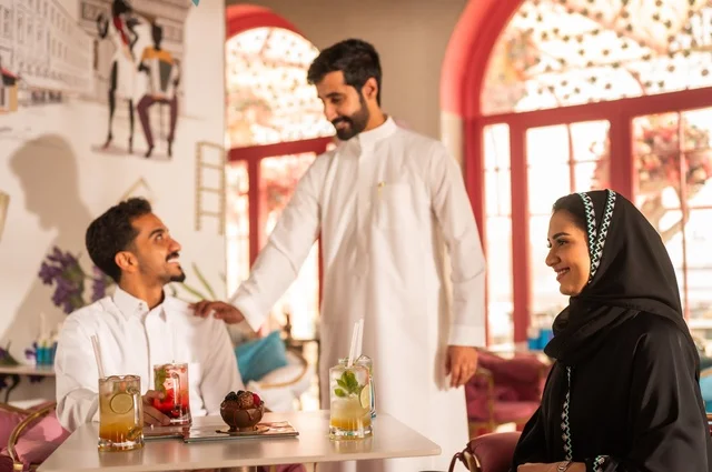 احتساء المشروب المفضل في كوفي شوب، قضاء أوقات ممتعة مع الأصدقاء، تطوير علاقات اجتماعية ناجحة بين الأشخاص،النقاش والحوار في الأجواء الهادئة، صورة لزملاء عربيين خليجيين سعوديين مبتسمين يجلسون في إحدى المقاهي الراقية بتعابير السعادة والسرور