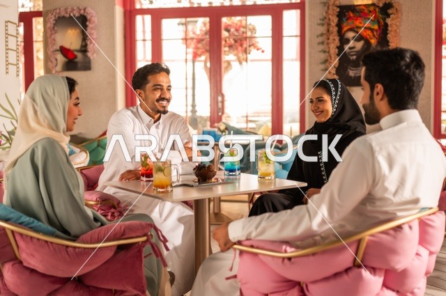 بناء علاقات اجتماعية ناجحة بين الأشخاص،النقاش والحوار في الأجواء الهادئة، قضاء أوقات ممتعة مع الأصدقاء، مشاركة المشروبات الباردة والحلويات،  صورة لزملاء عربيين خليجيين سعوديين مبتسمين يجلسون في إحدى المقاهي الراقية بتعابير السعادة والسرور