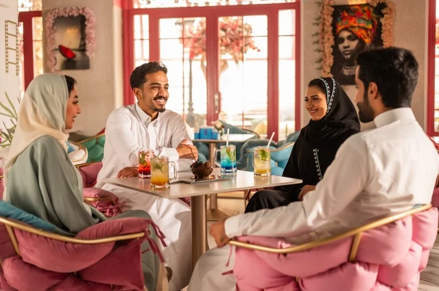بناء علاقات اجتماعية ناجحة بين الأشخاص،النقاش والحوار في الأجواء الهادئة، قضاء أوقات ممتعة مع الأصدقاء، مشاركة المشروبات الباردة والحلويات،  صورة لزملاء عربيين خليجيين سعوديين مبتسمين يجلسون في إحدى المقاهي الراقية بتعابير السعادة والسرور