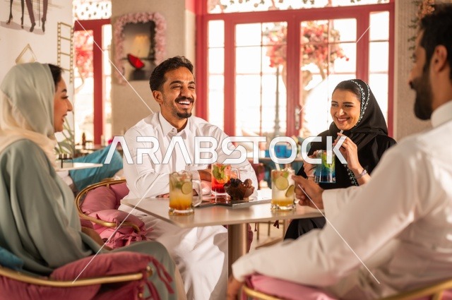 بناء علاقات اجتماعية ناجحة بين الأشخاص،النقاش والحوار في الأجواء الهادئة، قضاء أوقات ممتعة مع الأصدقاء، مشاركة المشروبات الباردة والحلويات،  صورة لزملاء عربيين خليجيين سعوديين مبتسمين يجلسون في إحدى المقاهي الراقية بتعابير السعادة والسرور