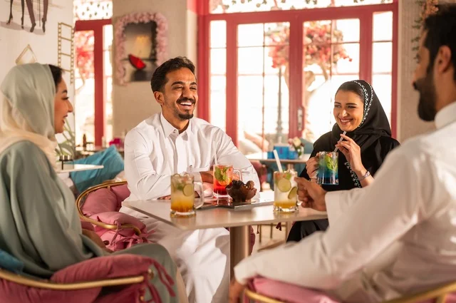 بناء علاقات اجتماعية ناجحة بين الأشخاص،النقاش والحوار في الأجواء الهادئة، قضاء أوقات ممتعة مع الأصدقاء، مشاركة المشروبات الباردة والحلويات،  صورة لزملاء عربيين خليجيين سعوديين مبتسمين يجلسون في إحدى المقاهي الراقية بتعابير السعادة والسرور