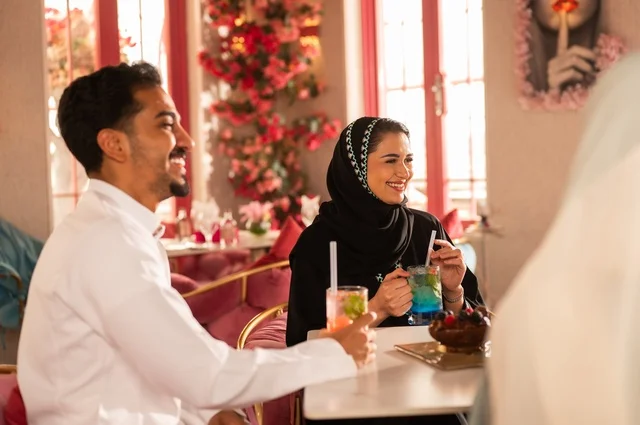 Meeting new friends and building social relationships, spending enjoyable times with friends, developing successful social relationships among people, discussion and dialogue in calm atmospheres, a picture of two smiling Saudi Gulf Arab colleagues sitting in one of the upscale cafes with expressions of happiness and joy.