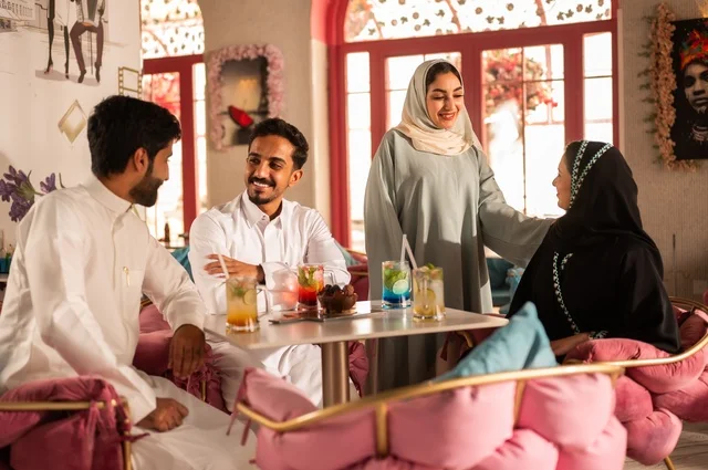 قضاء أوقات ممتعة مع الأصدقاء، النقاش والحوار في الأجواء الهادئة، مشاركة المشروبات الباردة والحلويات والفواكه، بناء علاقات اجتماعية ناجحة بين الأشخاص، صورة مقربة لزملاء عربيين خليجيين اماراتيين مبتسمين يجلسون في إحدى المقاهي الراقية بتعابير السعادة والسرور