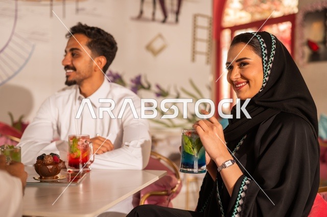 زوجان عربيان خليجيان سعوديان يستمتعان بتبادل الحديث  في احد المقاهي السعودية، تناول المشروبات الباردة، نقاشات وحوارات، قضاء أوقات ممتعة، أجواء عائلية سعيدة، مقهى سعودي