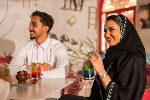 زوجان عربيان خليجيان سعوديان يستمتعان بتبادل الحديث  في احد المقاهي السعودية، تناول المشروبات الباردة، نقاشات وحوارات، قضاء أوقات ممتعة، أجواء عائلية سعيدة، مقهى سعودي