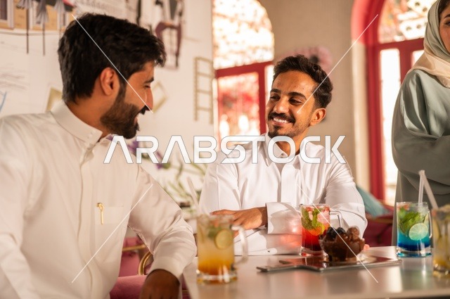 تقوية روابط الصداقة من جديد، قضاء أوقات ممتعة مع الأصدقاء، تطوير علاقات اجتماعية ناجحة بين الأشخاص، النقاش والحوار في الأجواء الهادئة، صورة لشابان عربيان خليجيان سعوديان مبتسمين يجلسون في إحدى المقاهي الراقية بتعابير السعادة والسرور