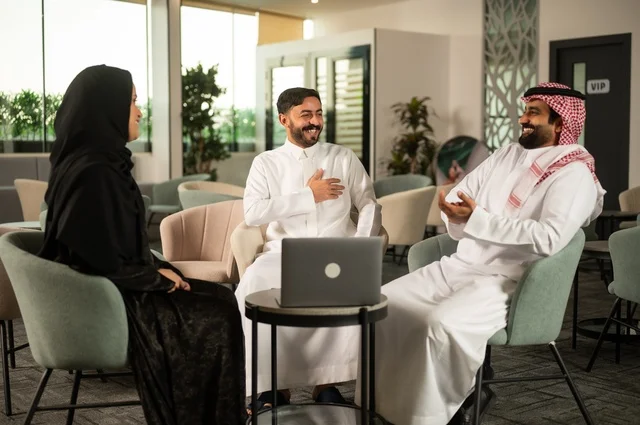 A business meeting abroad, teamwork and team spirit, discussing plans and strategies, using a laptop to take notes, professionalism and dedication to achievement, a Gulf Arab Saudi team exchanging ideas and opinions, ensuring a clear and comprehensive understanding of the work.