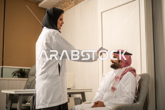 Measuring temperature using an electronic thermometer, providing consultations in medical centers, working in the health sectors, an Arab Gulf Saudi female doctor wearing a white coat examining the medical condition of a patient wearing a ghutrah and traditional thobe, dialogue with patients to uncover the condition.