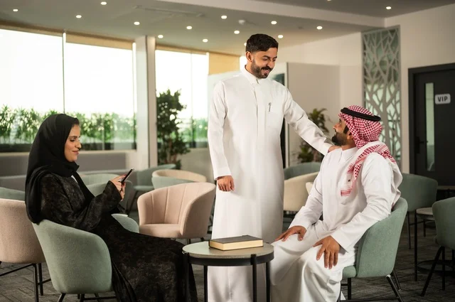 زملاء عمل في اجتماع خارج الشركة, إمرأة عربية خليجية سعودية ترتدي الحجاب والعباءة تقوم باستخدام الجوال برفقة أصدقائها, دمج التكنولوجيا والتقنية بالحياة الروتينية، الجلوس في احدى الكافيهات الراقية، جلسات تعارف وديه