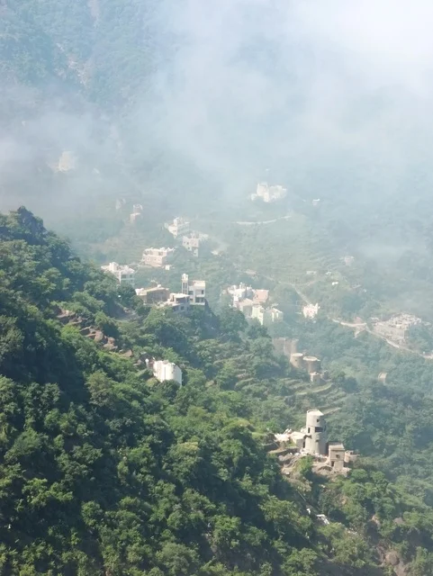 المدرجات الزراعية على السفوح الجبلية، البيوت القديمة الشعبية على جبال فيفاء في جازان جنوب المملكة العربية السعودية، القمم والمرتفعات الصخرية في النهار، مكان ومنطقة سياحية طبيعية، الأشجار والنباتات ومساحات الطبيعة الخضراء