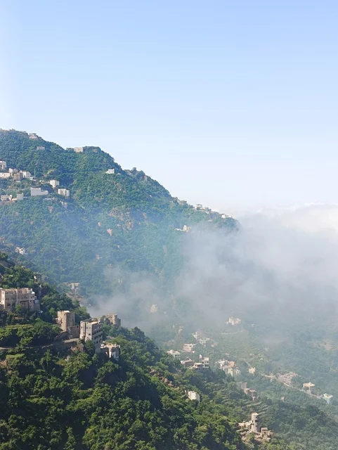 The old traditional houses on the mountains of Faifa in Jazan, southern Saudi Arabia, the peaks and rocky elevations during the day, a natural tourist place and area, the trees and plants and areas of green nature, the agricultural terraces on the mountain slopes.