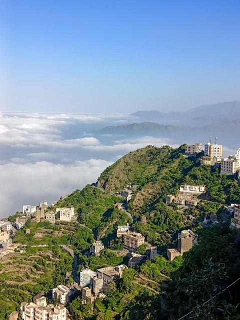 The agricultural terraces on the mountain slopes, the old traditional houses on the Al-Fifah mountains in Jazan, southern Saudi Arabia, the peaks and rocky elevations during the day, a natural tourist place and area, the trees, plants, and green nature spaces.