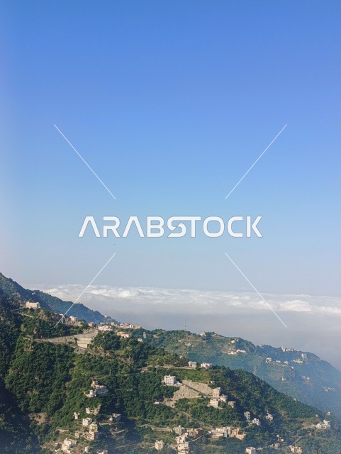المدرجات الزراعية على السفوح الجبلية، البيوت القديمة الشعبية على جبال فيفاء في جازان جنوب المملكة العربية السعودية، القمم والمرتفعات الصخرية في النهار، مكان ومنطقة سياحية طبيعية، الأشجار والنباتات ومساحات الطبيعة الخضراء