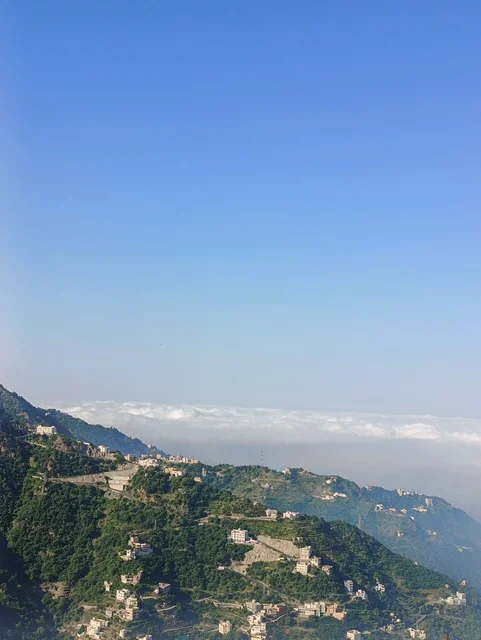 المدرجات الزراعية على السفوح الجبلية، البيوت القديمة الشعبية على جبال فيفاء في جازان جنوب المملكة العربية السعودية، القمم والمرتفعات الصخرية في النهار، مكان ومنطقة سياحية طبيعية، الأشجار والنباتات ومساحات الطبيعة الخضراء