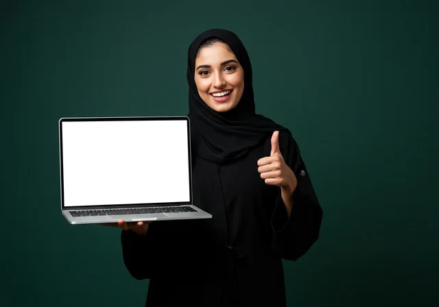 اشارة بإصبع الأبهام إلى الأعلى الأعجاب، خلفية شاشة بيضاء على حاسب محمول, النظر الى الكاميرا بتعابير السرور,  العروض والإعلانات التسويقية, بورتريه مقرب لإمرأة عربية خليجية سعودية محجبة ترتدي العباءة تمسك بيدها موبايل حديث, خلفية خضراء داكنة