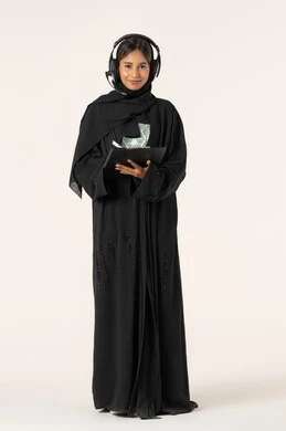 Writing daily tasks and goals, noting and recording observations and information on paper, a portrait of a young Arab Gulf Emirati woman wearing an abaya and hijab and headphones, holding a folder and a pen in her hand, organizing and managing business, full-body, white background.